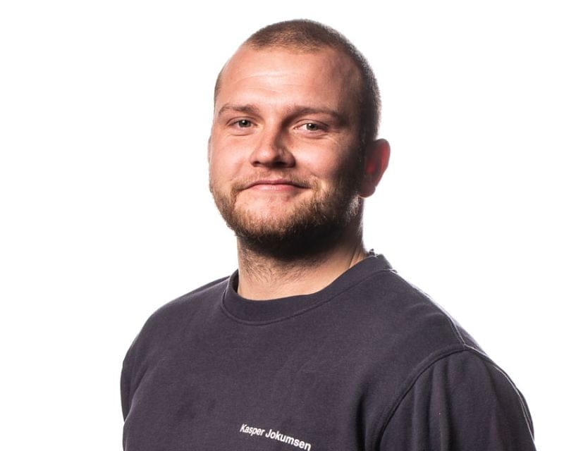Mand smiler iført mørk sweatshirt på hvid baggrund
